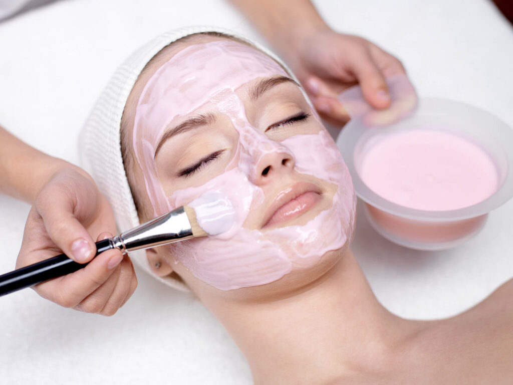 Young,Beautiful,Girl,Receiving,Pink,Facial,Mask,In,Spa,Beauty